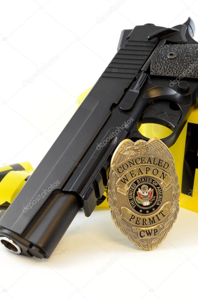 Closeup view of a handgun with a weapons badge and some police tape for law enforcement.