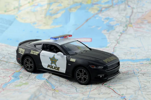 A scale model police car resting on top of a map for several law enforcement concepts.
