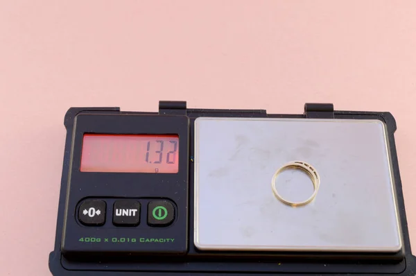 A set of digital scales weighs a gold ring that is going to be sold for scrap.