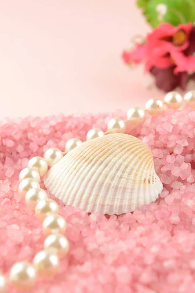 海のシェルと真珠の文字列は 女性的なタッチで暖かい魅力的なシーンのためのピンクのバス塩のベッドの間に横たわっています — ストック写真