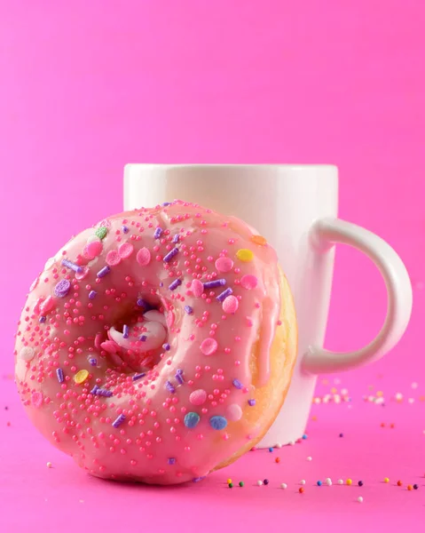 ピンクの背景にコーヒーカップとドーナツ — ストック写真