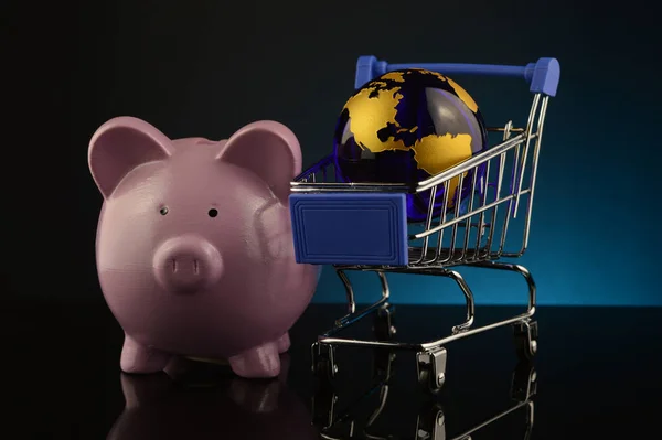 一个基于猪银行 地球仪和购物车的全球化购物账户的概念 — 图库照片