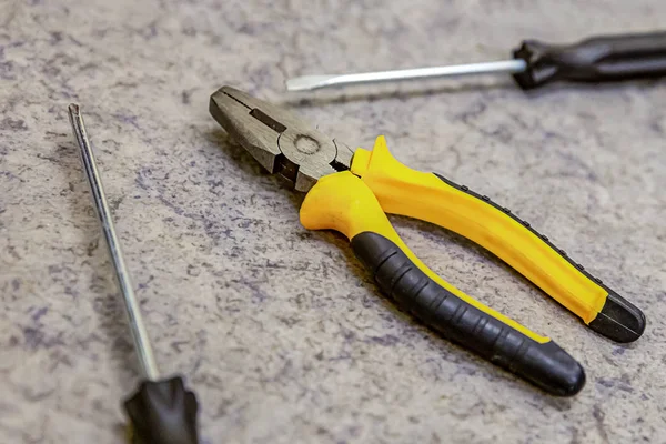 Żółte szczypce otoczone śrubokrętami zbliżenie ostrości w środku obrabianego narzędzia montażowego — Zdjęcie stockowe