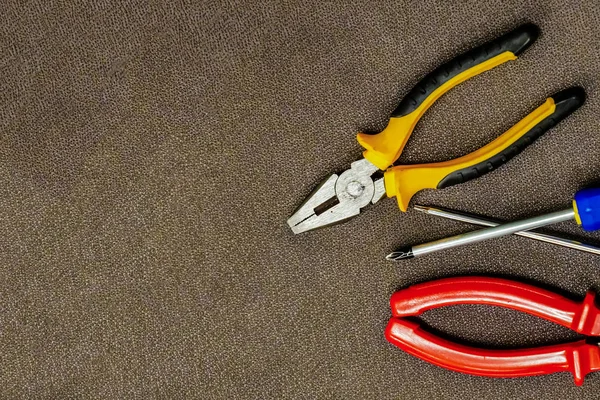 Handwerkzeug rote Zangen Paar Eisenschraubendreher Fixierung auf braunem Kopierraum Set-Design — Stockfoto