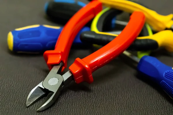 pile of tools of hand red nippers on the background of plastic pens screwdriver macro background construction