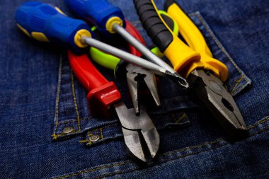 Parlak renkli kolları ile aletleri denim üzerinde yalan. tornavida tamir sanayi pliers çifti