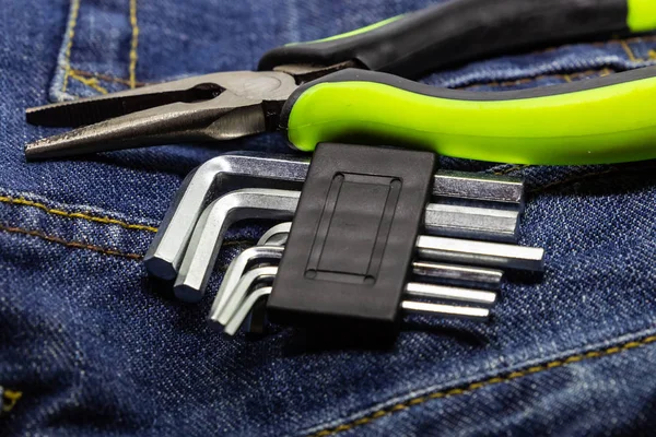 tools for furniture repair are scattered on working clothes. Pliers hexagonal wrench