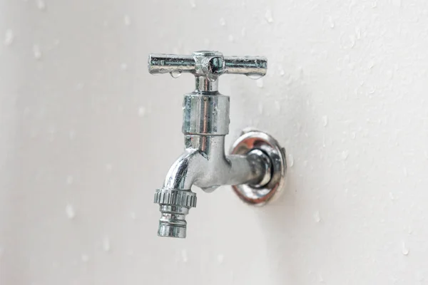 Beyaz arka plan su kaynağı ayarı üzerinde duvarda gümüş metal musluk yüzeyde basınç su damlaları — Stok fotoğraf