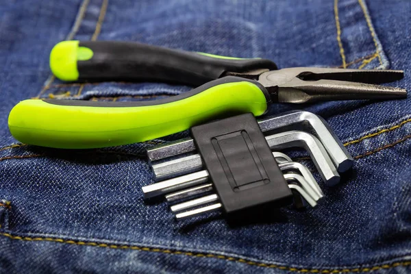 Grüne Zange schmalen Metall facettierten Schraubenschlüssel l-förmigen Set auf Denim dunklen Stoff Nahaufnahme — Stockfoto