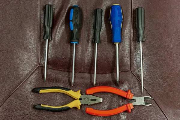 Conjunto vertical fila paralela de destornilladores un par de pinzas sobre un fondo oscuro herramientas de mano de diseño — Foto de Stock