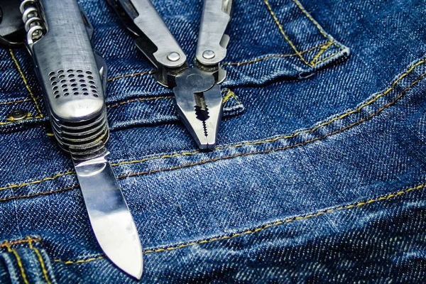 multifunctional set tools available quick knife pliers on a dark blue background jeans working clothes