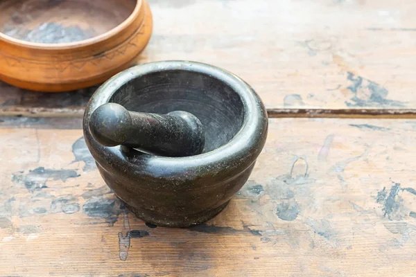Mortar old big black close-up culinary tool on a wooden table Traditional Stock Photo