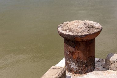 çamurlu bir nehrin arka planında eski paslı metal bollard demirleme tekneleri