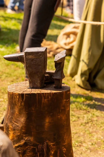 Yunque de hierro forja metal en un muñón de madera vertical foto soleada feria rural — Foto de Stock