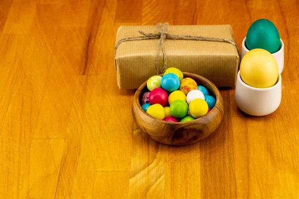 Пасхальный узор дизайн подарка корабль коричневые яйца пара зеленый желтый конфеты драже деревянный фон — стоковое фото