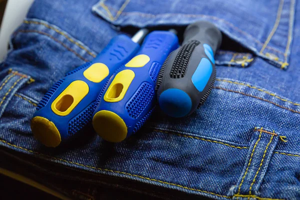 screwdriver pair rubber handle blue pocket jeans overalls repairman hand tools