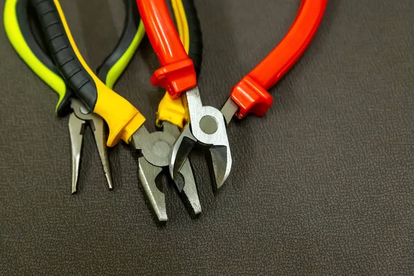 Åbne tænger byggeri værktøjer med flerfarvede håndtag rød gul på en mørk baggrund - Stock-foto