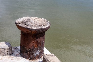 eski bir demir bollard yıpranmış nehir demirleme teknelerin bir taş iskele kenarında duruyor