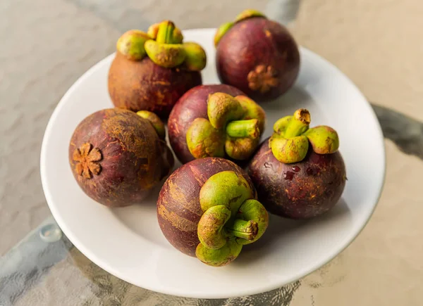 Frutas inteiras Mangostão frutas asiáticas frescas e deliciosas jazem em um prato branco — Fotografia de Stock
