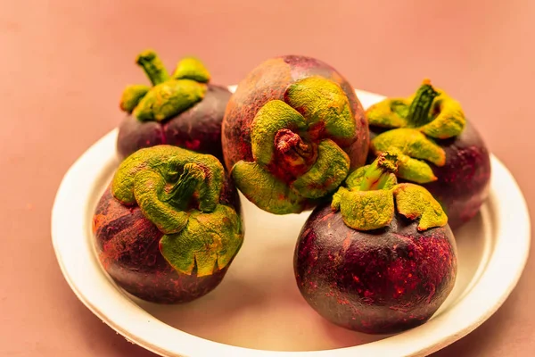 Mangosteen whole fruits lie on a white plate close up dessert asia — Stock Photo, Image