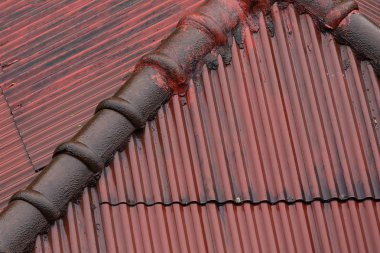 eski çatı koyu kırmızı kirli nervürlü doku. Eski evin çatısı yivli solmuş.