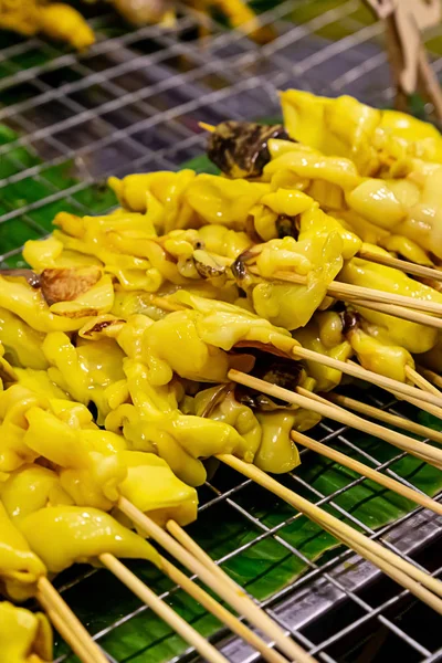 Шашлыки осьминога, приправленные желтым карри на деревянном шампуре, лежащем на решетке гриля — стоковое фото