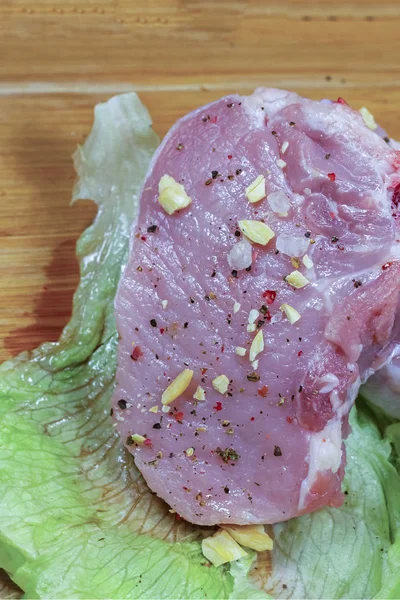 Bife de cordeiro, carne fresca temperada e salgada repousa sobre uma folha fresca de alface — Fotografia de Stock