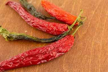 Uzun kurumuş kırmızı biber ve ahşap arka planda yeşil kapsül.