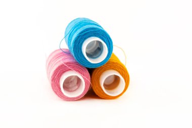 Üç rulo iplik yığını pembe, sarı ve mavi yakın plan beyaz arka plan