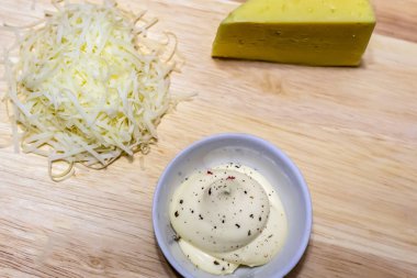 Yemek sosu rendelenmiş peynir ve mayonez. Ahşap arka planda acı biberle tatlandırılmış.