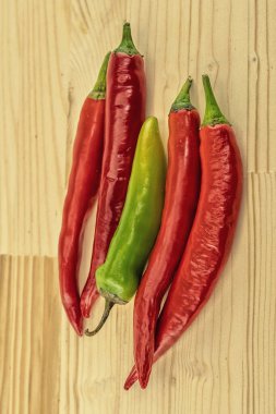 Ahşap arka planda kırmızı biber ve yeşil kapsül. Bir çift sebze.