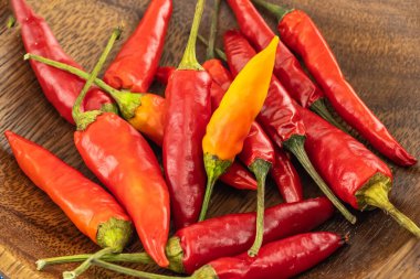 Sıcak kırmızı biber ahşap bir kase içinde yakın plan sebze arka planında.