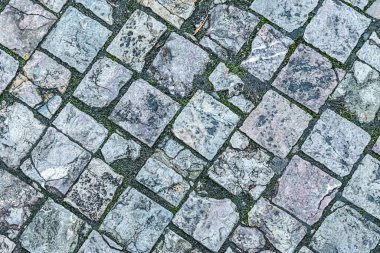 Kare gri mermer karolardan yapılmıştır. Arka plan yıpranmış ve kırılmış.