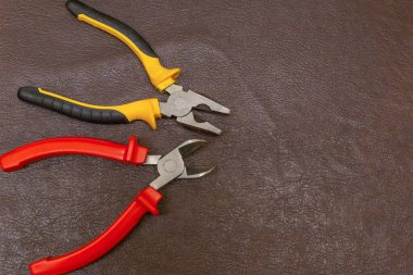 Kauçuk saplı bir çift kerpeten çok renkli kırmızı ve siyah, koyu arkaplanda sarı.