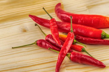 Büyük, olgun kırmızı biber ve küçük kırmızı biber kabuğu ahşap bir zemine saçılmış.