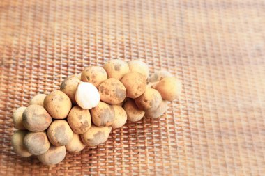 Tayland 'ın meyvesi, Longkong' un bir dalı hasır bir tahta yüzeyde bulunur.