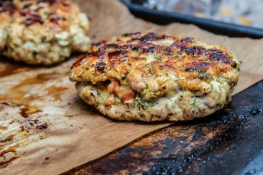 Kızarmış dereotlu tavuk pirzolası, yakın plan pişirme çarşafının üzerinde yatıyor.