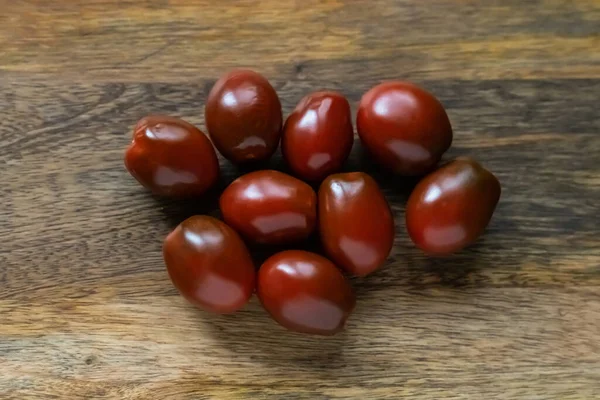 Tomates Cherry Rojo Oscuro Borgoña Espolvoreado Sobre Fondo Madera Fotos de stock libres de derechos