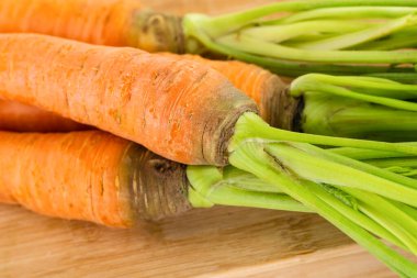 Tahta bir yüzey üzerinde yeşil tepeli bir grup taze sebze turuncu havuç.