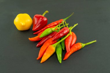 Siyah arka planda kırmızı ve sarı yuvarlak biber ve acı biber.