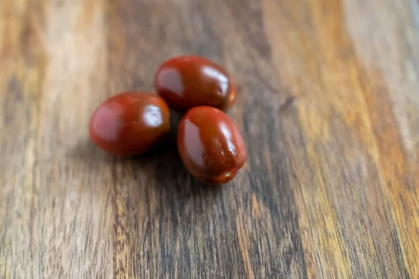 Tres Tomates Negros Kumato Cherry Sobre Fondo Madera Verticalmente —  Fotos de Stock