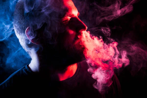 Mladý Muž Kouří Vydechuje Velké Mraky Barevných Modré Červené Kouře — Stock fotografie
