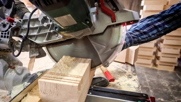 在木工车间工作的木匠的关闭 用圆锯为木头 在桌是锤子和许多工具圆锯 — 图库照片