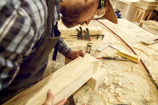 Carpenter in work clothes  doing woodwork in carpentry. small buiness owner work on wood plank in workshop