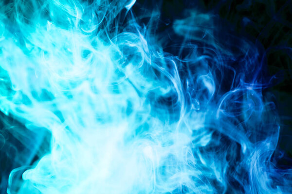Thick colorful blue smoke on a black isolated background. Background from the smoke of vap