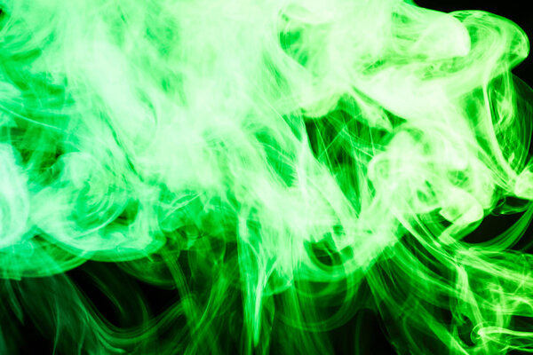 Thick colorful green smoke on a black isolated background. Background from the smoke of vap