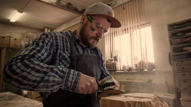 İş elbiseleri ve küçük buiness sahibi doğrama atölyesinde çalışan deneyimli marangoz işler kurulu bir açı öğütücü ile üzerinde bir çekiç ve birçok araç tablodur 