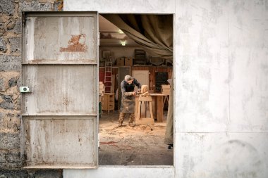 Takım elbiseli bir genç adam marangoz, gözlük bir insan kafası bir ağaç testereleri, sokaktan bir açı değirmeni atölye kullanarak, görüntüleme