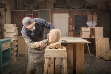 Genç adam marangoz bir takım, gözlük yakından bir insan kafası atölye çalışması için araçları bir sürü etrafında bir açı değirmeni kullanarak bir ağaç testereleri