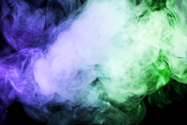 Thick colorful blue and green smoke on a black isolated background. Background from the smoke of vap